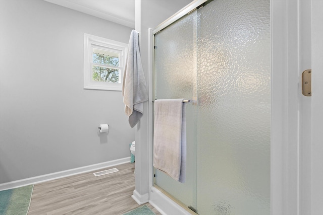 bathroom with hardwood / wood-style flooring, toilet, and a shower with shower door