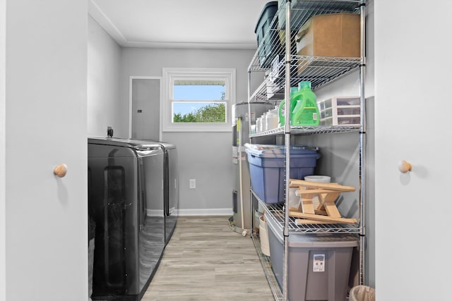 washroom with light wood-type flooring, washer and clothes dryer, and water heater