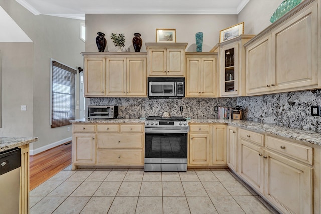 kitchen featuring light wood-type flooring, appliances with stainless steel finishes, a wealth of natural light, and ornamental molding