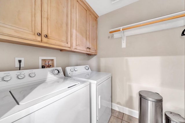 clothes washing area featuring light tile patterned floors, cabinets, and washing machine and dryer