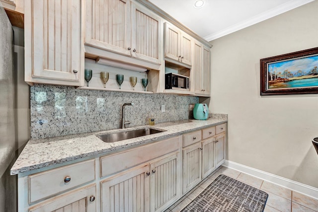 kitchen with crown molding, light tile patterned floors, sink, light stone countertops, and decorative backsplash