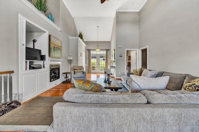 living room featuring hardwood / wood-style floors, french doors, ornamental molding, high vaulted ceiling, and ceiling fan