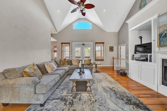 living room with high vaulted ceiling, french doors, ceiling fan, and light hardwood / wood-style flooring