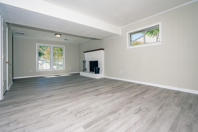 unfurnished living room with a brick fireplace, crown molding, and light hardwood / wood-style floors