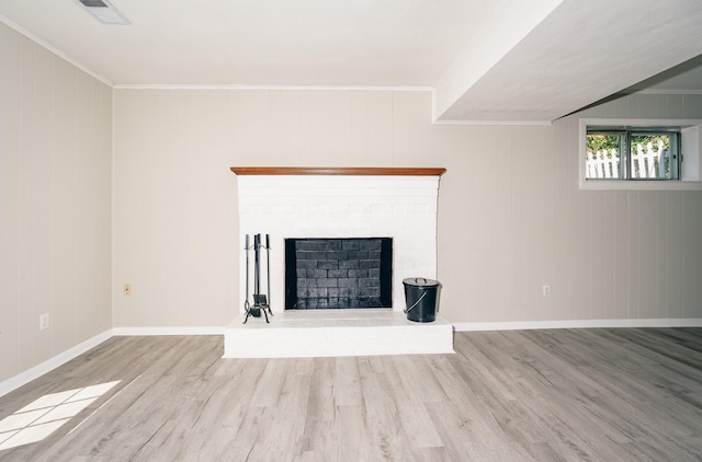 unfurnished living room featuring light wood-type flooring, a brick fireplace, ornamental molding, and wooden walls