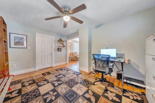 home office with hardwood / wood-style floors, ceiling fan, and a textured ceiling