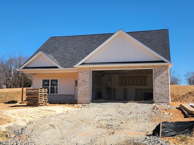 view of front of property featuring a garage, brick siding, and roof with shingles