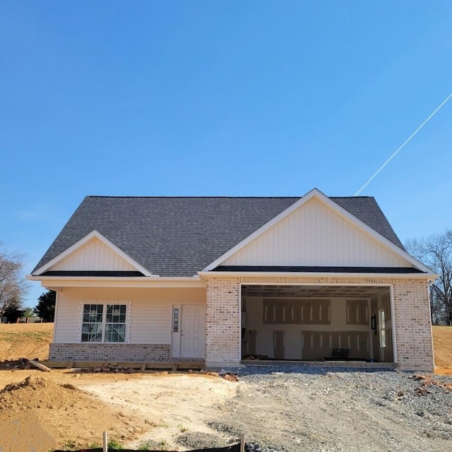 view of front facade featuring brick siding, a shingled roof, and a garage