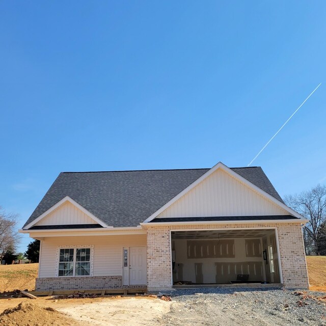 exterior space featuring a garage, brick siding, and roof with shingles