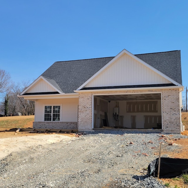 view of front of property featuring an attached garage, brick siding, driveway, and roof with shingles