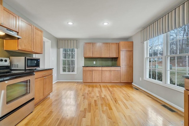 kitchen with under cabinet range hood, stainless steel appliances, visible vents, backsplash, and light wood finished floors