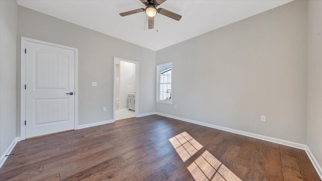 spare room featuring dark wood-type flooring, a ceiling fan, and baseboards