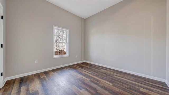 spare room featuring dark wood-style floors and baseboards