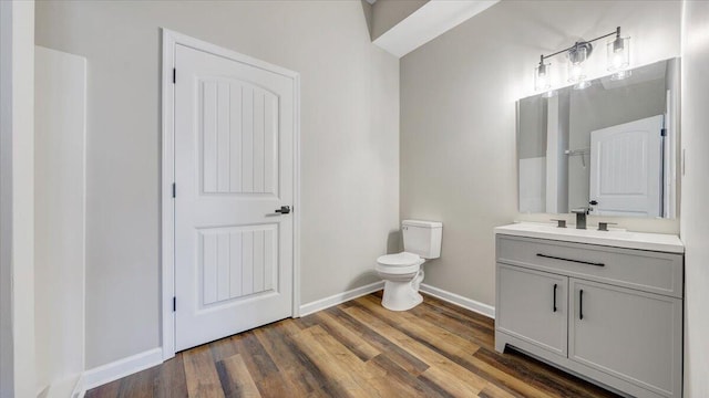 bathroom with toilet, baseboards, wood finished floors, and vanity