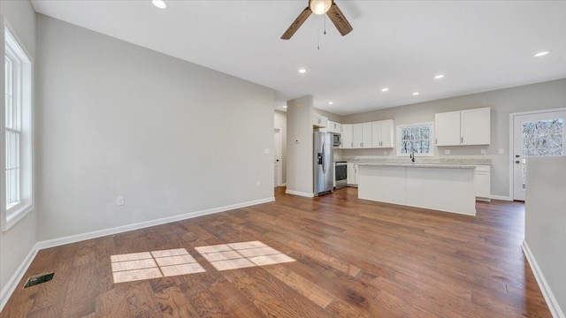 unfurnished living room with recessed lighting, visible vents, dark wood-type flooring, a sink, and baseboards