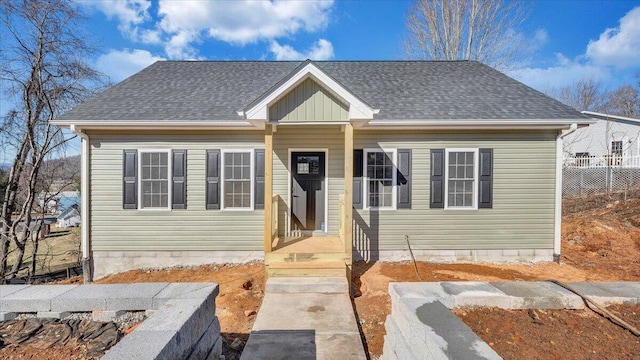 bungalow-style home with a shingled roof and fence