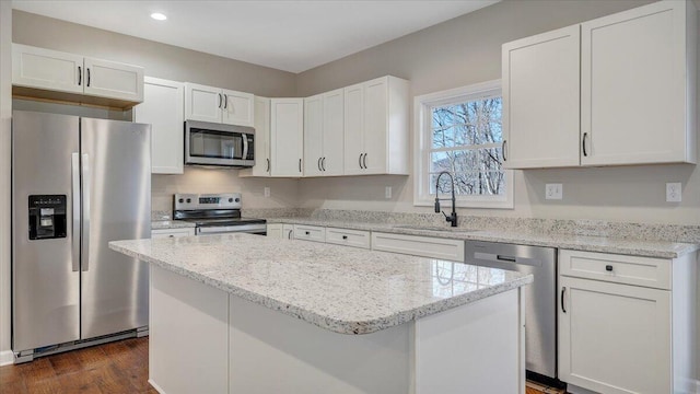 kitchen featuring stainless steel appliances, white cabinetry, a sink, and light stone counters