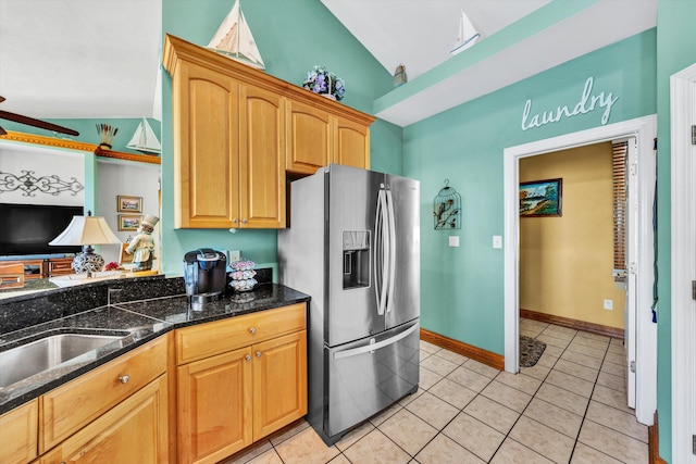 kitchen with stainless steel fridge with ice dispenser, dark stone counters, lofted ceiling, and light tile patterned floors