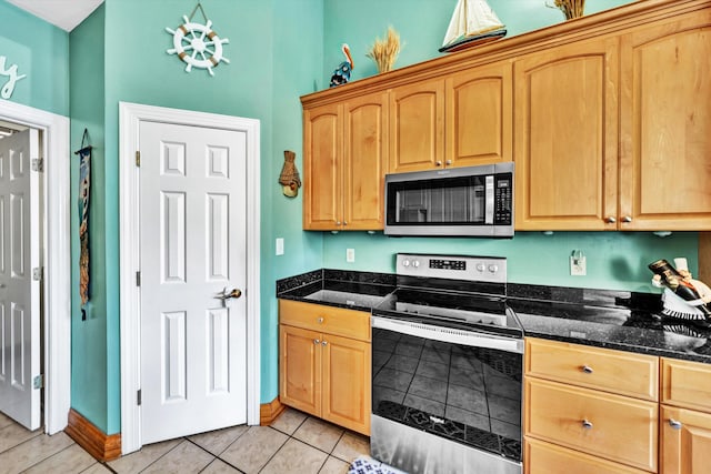 kitchen with stainless steel appliances, dark stone countertops, and light tile patterned flooring