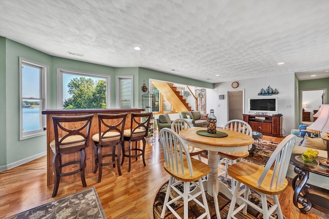 dining area with light hardwood / wood-style floors and a textured ceiling