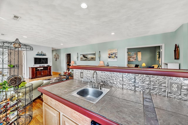 kitchen featuring tile countertops, a textured ceiling, wood-type flooring, sink, and light brown cabinets