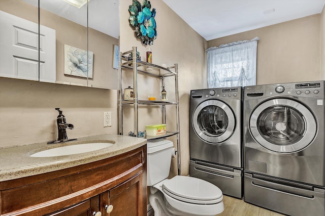 laundry room featuring light hardwood / wood-style flooring, washer and clothes dryer, and sink