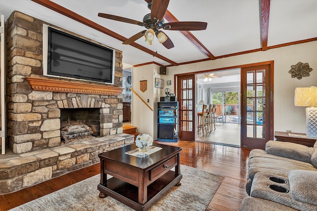 living room with beamed ceiling, a fireplace, hardwood / wood-style floors, ornamental molding, and ceiling fan