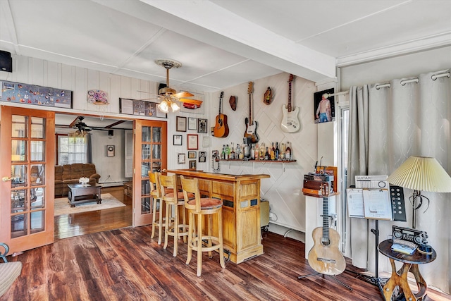 interior space with ceiling fan, wooden walls, and dark wood-type flooring