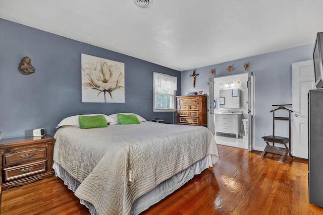 bedroom with ensuite bathroom and hardwood / wood-style flooring