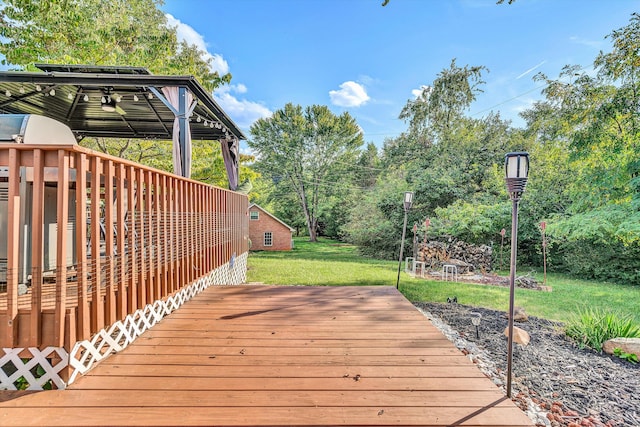 wooden deck with ceiling fan, a gazebo, and a lawn