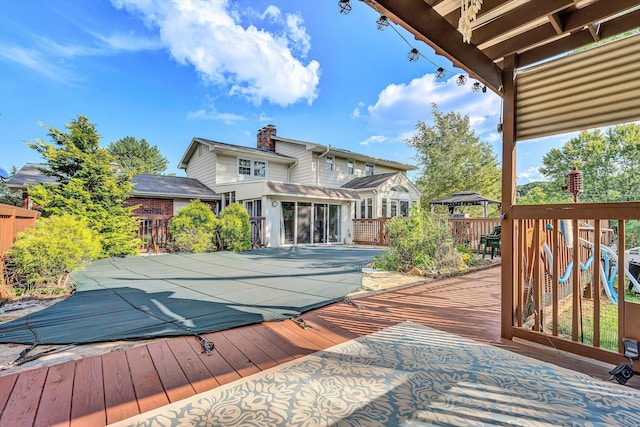 wooden deck with a gazebo, a covered pool, and a sunroom