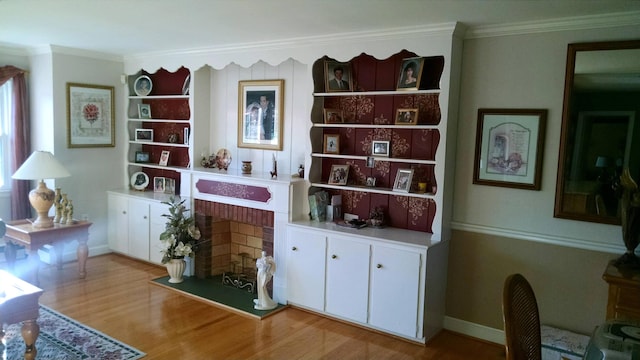 living area featuring crown molding, light hardwood / wood-style floors, and a brick fireplace