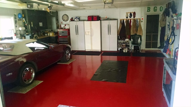 garage featuring a garage door opener, white refrigerator with ice dispenser, and white fridge