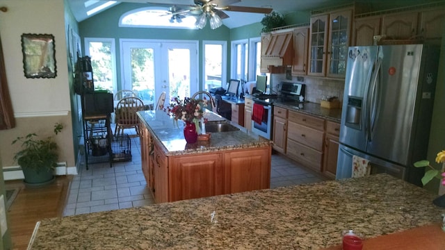 kitchen featuring appliances with stainless steel finishes, ceiling fan, french doors, a center island with sink, and sink