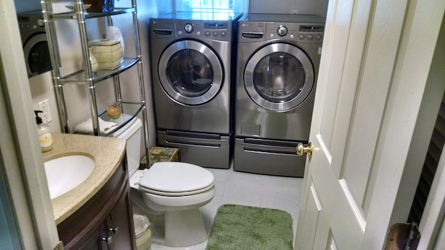 bathroom with washer and clothes dryer, toilet, and tile patterned flooring