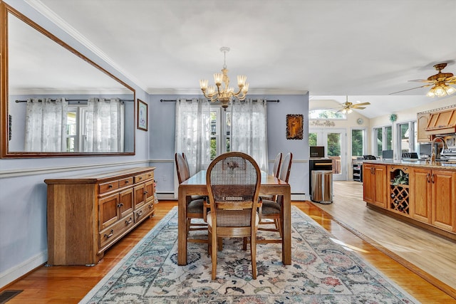 dining area with light wood-type flooring, ceiling fan with notable chandelier, vaulted ceiling, a baseboard radiator, and crown molding