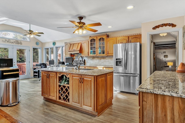 kitchen featuring light wood-type flooring, stainless steel fridge, ceiling fan, and light stone counters