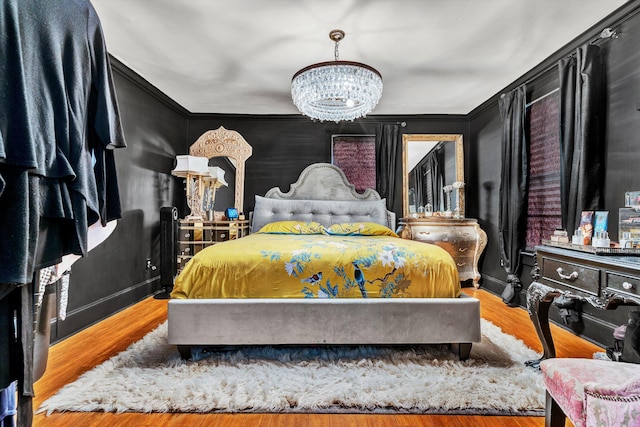 bedroom featuring hardwood / wood-style flooring, crown molding, and a chandelier