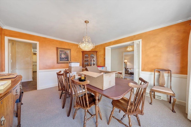 carpeted dining area featuring a notable chandelier and crown molding