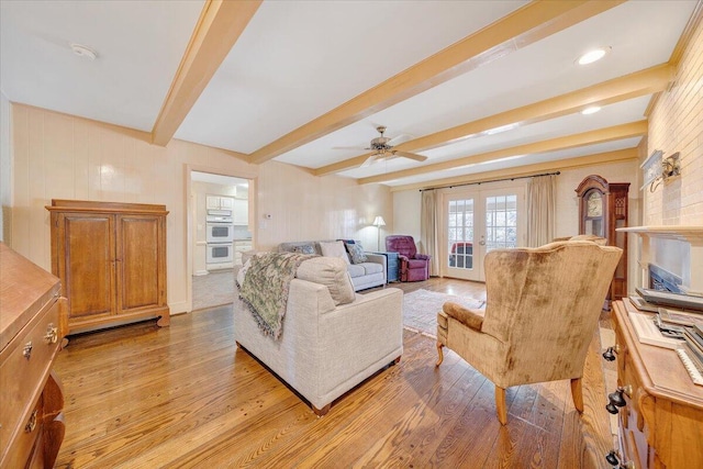 living room featuring ceiling fan, beam ceiling, french doors, and light hardwood / wood-style flooring