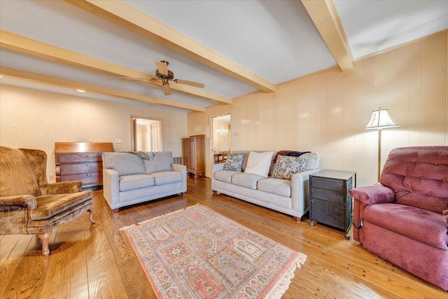 living room with hardwood / wood-style floors, ceiling fan, and beam ceiling