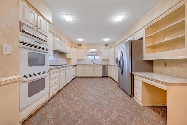 kitchen with decorative backsplash, sink, stainless steel appliances, and wall chimney range hood