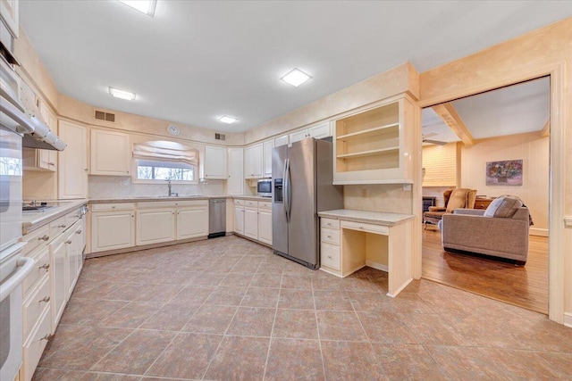 kitchen with tasteful backsplash, sink, white cabinets, and appliances with stainless steel finishes