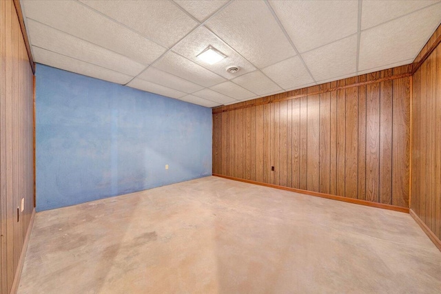 spare room featuring wood walls and a drop ceiling