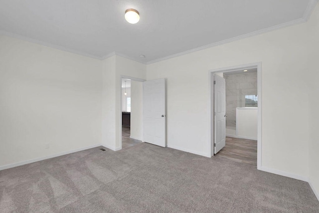 unfurnished bedroom featuring light carpet, crown molding, and ensuite bath