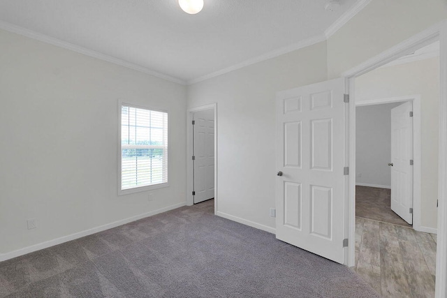 unfurnished bedroom featuring a closet, wood-type flooring, a walk in closet, and ornamental molding