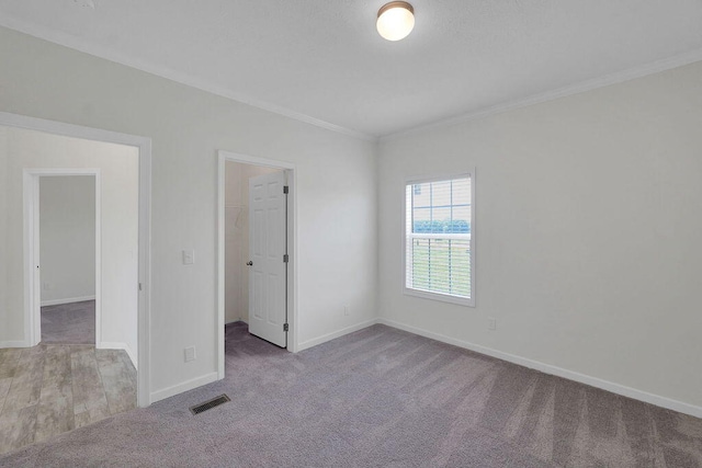 unfurnished bedroom with light carpet, a walk in closet, a closet, and crown molding