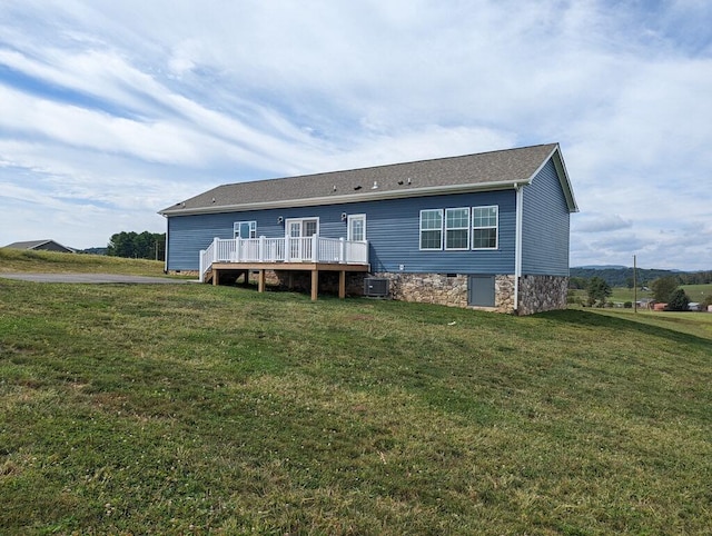 rear view of property featuring central air condition unit, a wooden deck, and a yard