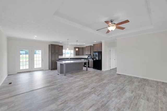 kitchen featuring light wood-type flooring, decorative light fixtures, a kitchen island, ceiling fan, and black refrigerator with ice dispenser