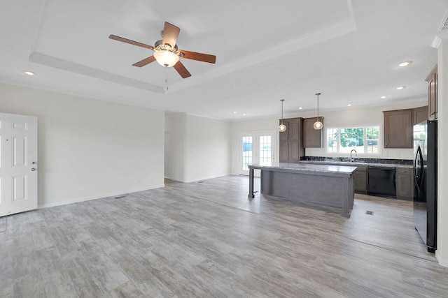 kitchen featuring a kitchen island, pendant lighting, black appliances, a tray ceiling, and ceiling fan